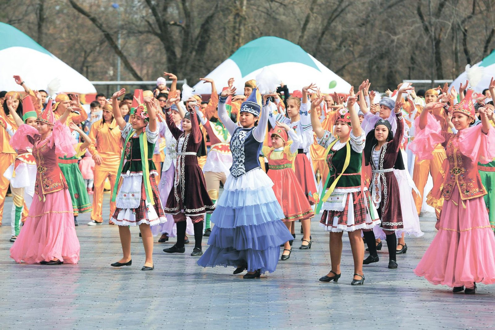 Vibrant group celebration with dancers in traditional costumes performing outdoors.